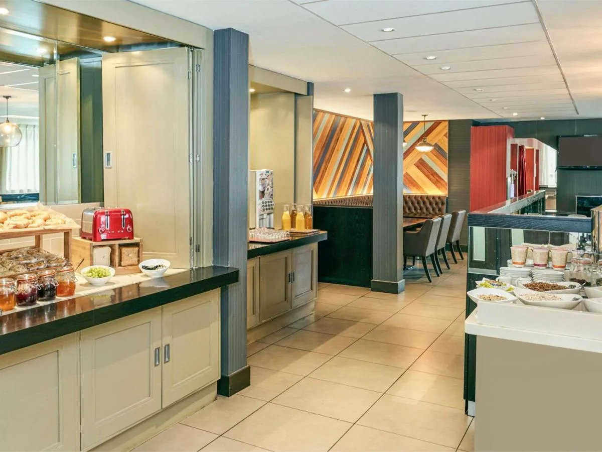 a large restaurant with a buffet line with food at ibis Belfast Queens Quarter in Belfast
