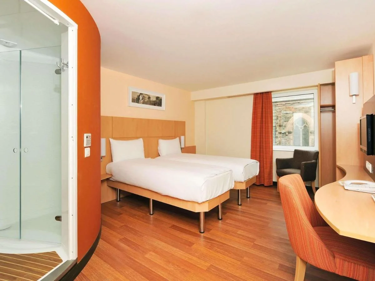 a hotel room with a bed and a desk and a window at ibis Belfast Queens Quarter in Belfast