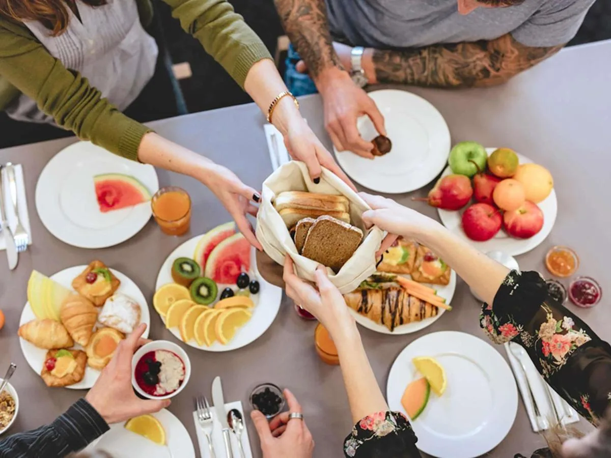 a group of people holding hands over a table with food at ibis Belfast Queens Quarter in Belfast