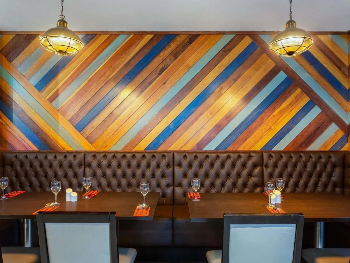 a dining room with two tables and a colorful wall at ibis Belfast Queens Quarter in Belfast